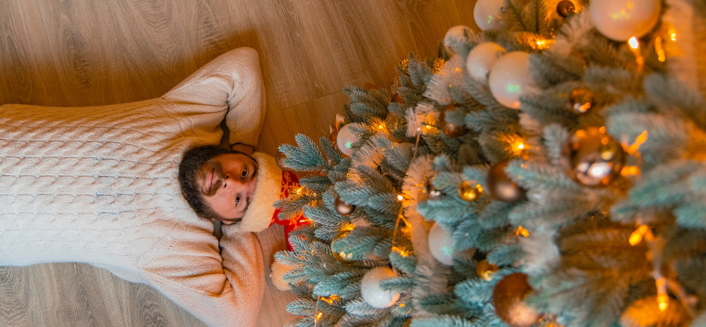 Mann liegt entspannt unter Weihnachtsbaum