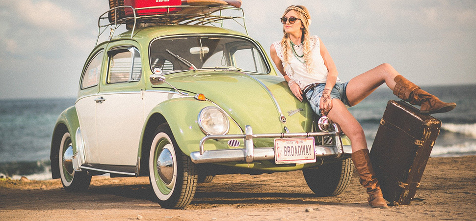 Frau sitzt auf der Motorhaube des Autos