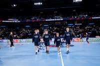 Vier Jungs tragen zwei Getränkekisten über ein Handballfeld
