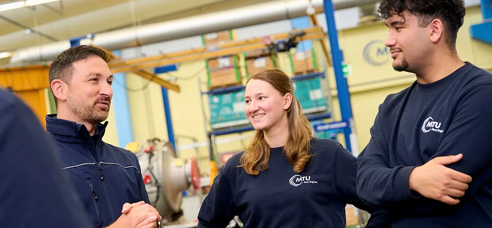 Tag der Ausbildung bei MTU Aero Engines Drei Mitarbeitende in MTU Aero Engines Pullovern unterhalten sich
