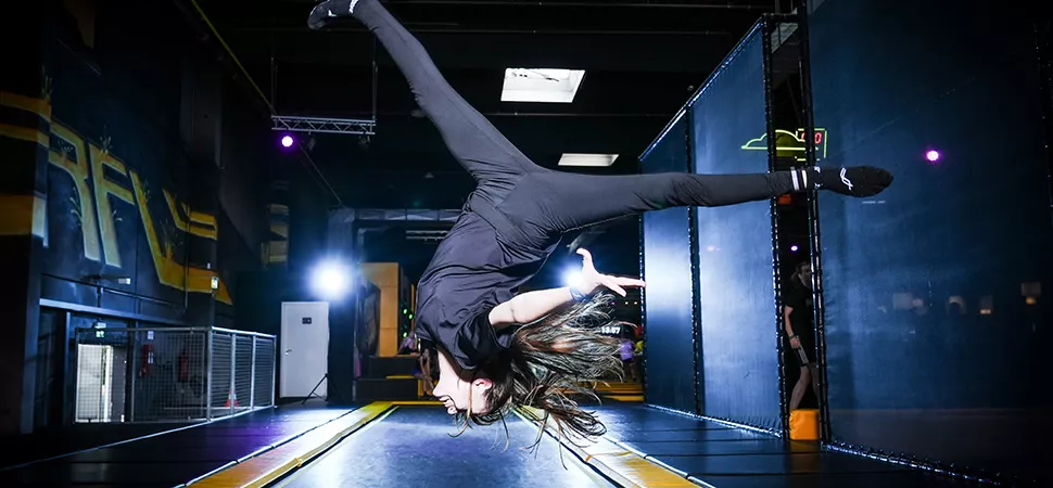Trampolinspringerin im Superfly München Eine Trampolinspringerin macht überkopf einen Spagat im Sprung