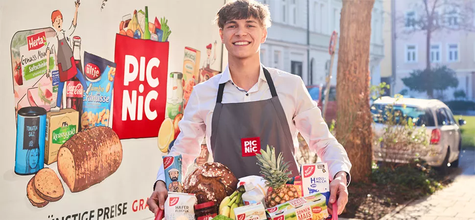 Ein junger Mann mit Schütze trägt einen Korb Lebensmittel