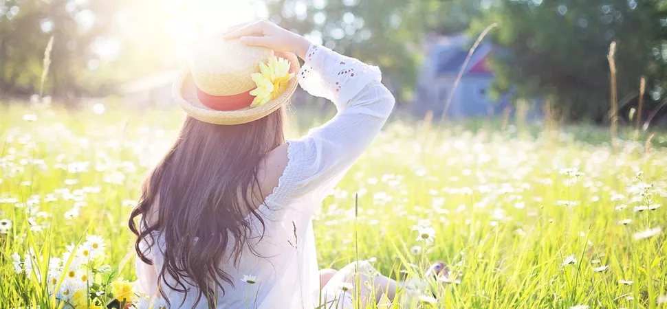 Frau genießt Sonnenstrahlen auf Blumenwiese Frau genießt Sonnenstrahlen auf Blumenwiese
