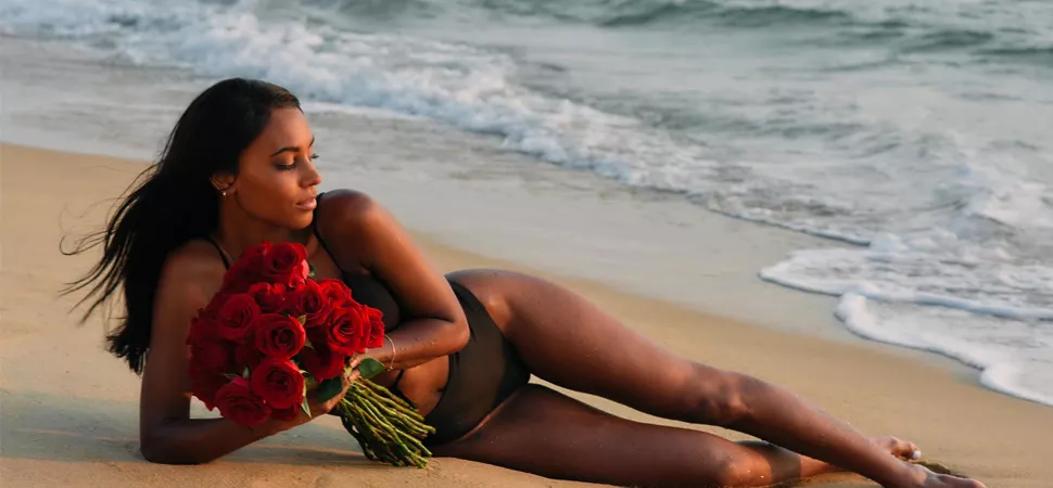 Bachelorette liegt mit Rosen am Strand