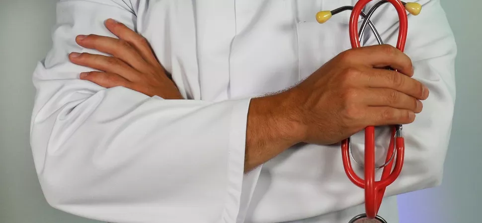 Ein Arzt mit überschränkten Armen und einem Stethoskop in der Hand Arzt Symbolbild