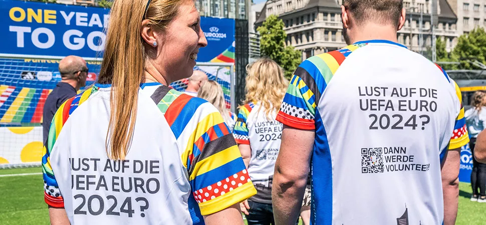 UEFA EURO 2024 - Werde Volunteer! Eine Frau und ein Mann tragen Shirts auf deren Rücken "Lust auf die UEFA EURO 2024?" steht