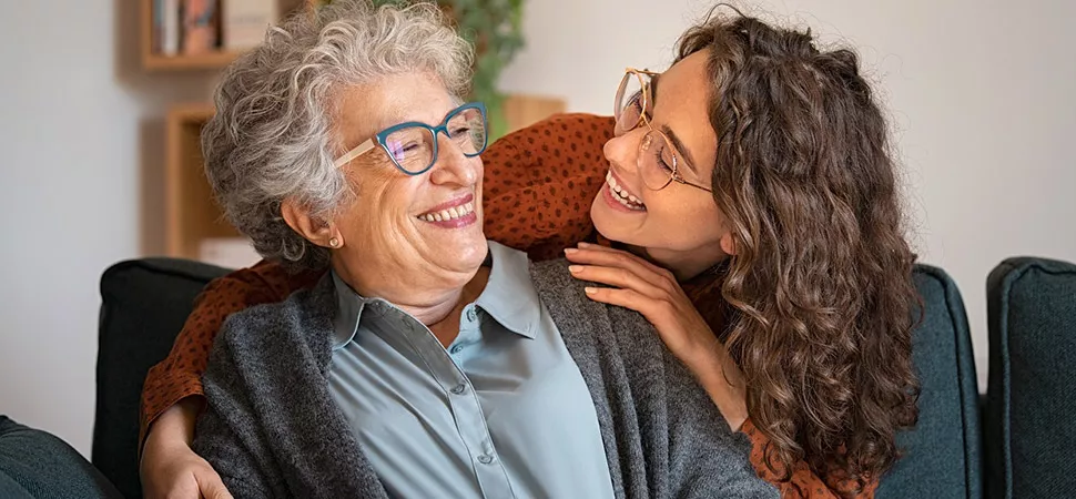Gesundheit im Alter Junge Frau umarmt eine ältere Frau.