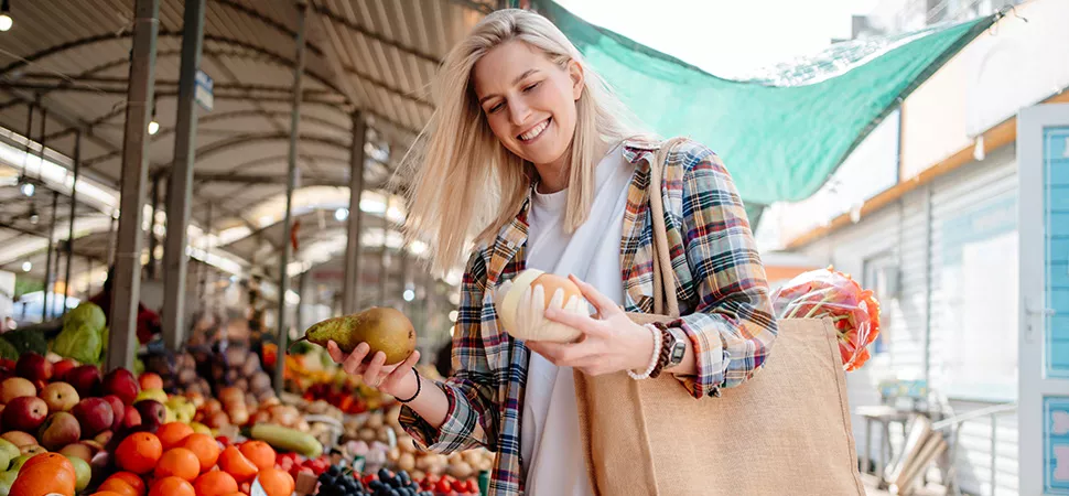 Frau auf dem Wochenmarkt Frau auf dem Wochenmarkt hält zwei Früchte in der Hand