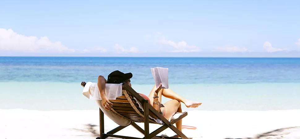 Frau am Strand Frau liegt auf einem Liegestuhl mit Meerblick und liest ein Buch