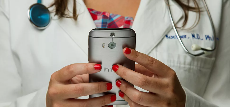 Doktorin hält ein Handy in der Hand
