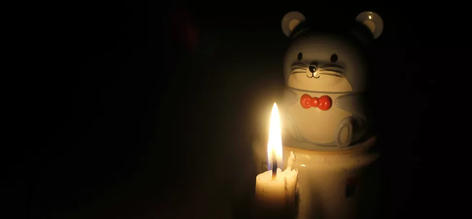 Eine Keramikfigur in Form eines Bärchens wird von Kerzenlicht angeschienen