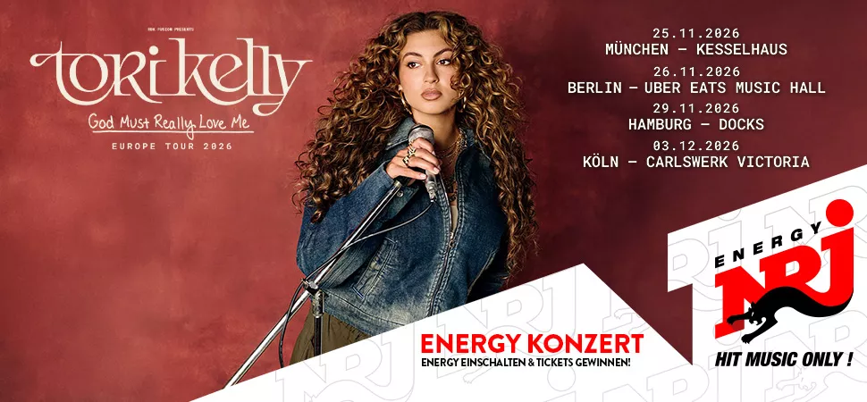 Frau in Jeansjacke mit langen Locken hält ein Mikrofon in der Hand