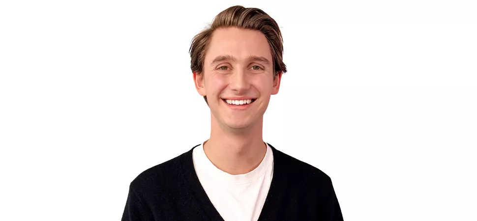 Blonder junger Mann mit weißem Shirt und schwarzem Cardigan