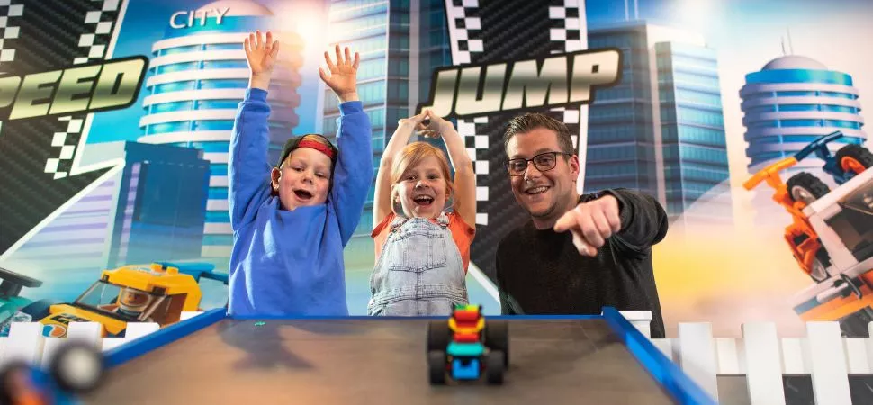 Ein Mann und zwei Kinder spielen mit LEGO Spielzeug
