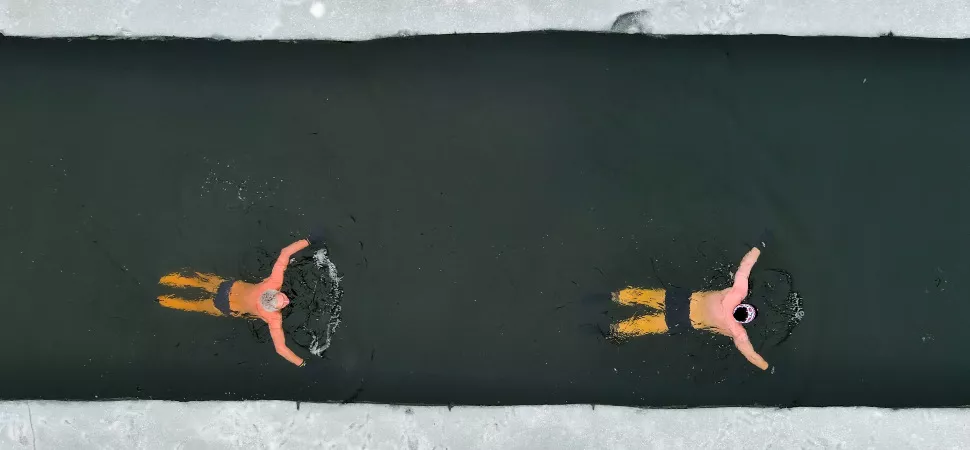 Header Eisbaden 970 Zwei Personen schwimmen im Wasser mit Eis umgeben