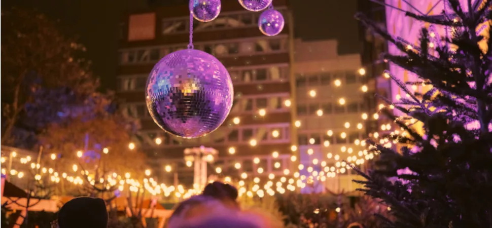 Header Punschwald Discokugeln vor einer weihnachtlich beleuchteten Kulisse mit Tannenbäumen