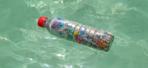 Mikroplastik in einer Plastikflasche, die im Wasser schwimmt