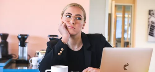 Eine Frau sitzt gelangweilt vor ihrem Laptop
