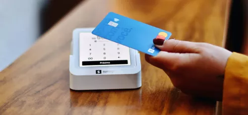 Close Up einer Hand mit einer Bankkarte, die an ein Kartenlesegerät gehalten wird