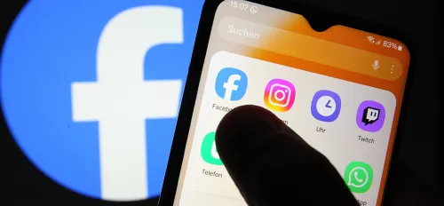 Auf einem Smartphone sind verschiedene Apps zu sehen - darunter Facebook. Dahinter wurde auf einem Smartphone das Facebook-Logo geöffnet. 