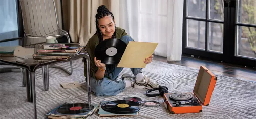 Ein Mädchen sitzt auf dem Boden und schaut sich eine Vinylplatte an.