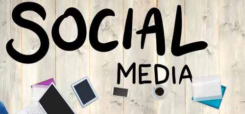 Ein Tisch von oben mit einem Laptop drauf, darüber steht "Social Media"