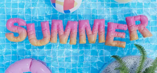 Ein Pool von oben mit einem Schriftzug SUMMER aus aufblasbaren Buchstaben