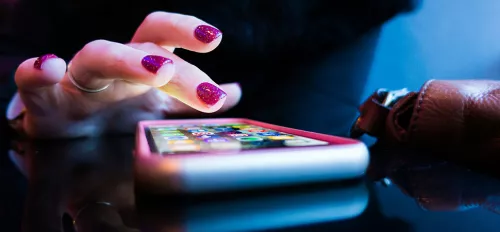 Hand mit pinken Nägeln tippt auf ein Smartphone