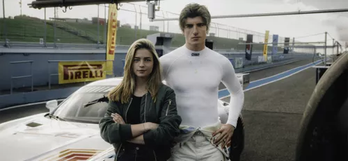 Lisa-Marie Koroll als Sarah Jenkins und Amin Baahmed als Dante Annunziata stehen vor einem Rennauto.