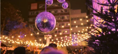 Discokugeln vor einer weihnachtlich beleuchteten Kulisse mit Tannenbäumen