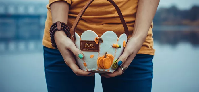 Eine Frau hält einen herbstlichen Korb in beiden Händen.