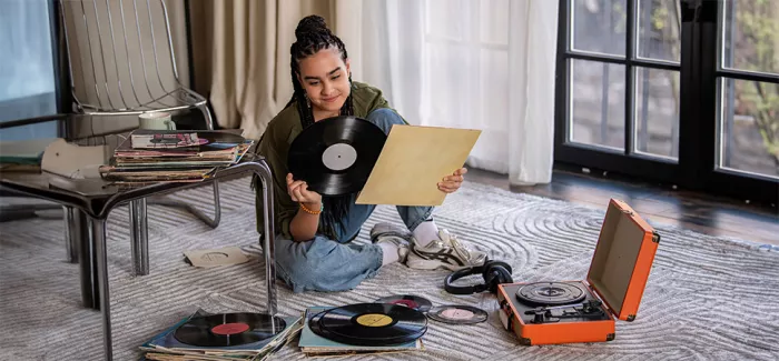 Ein Mädchen sitzt auf dem Boden und schaut sich eine Vinylplatte an.