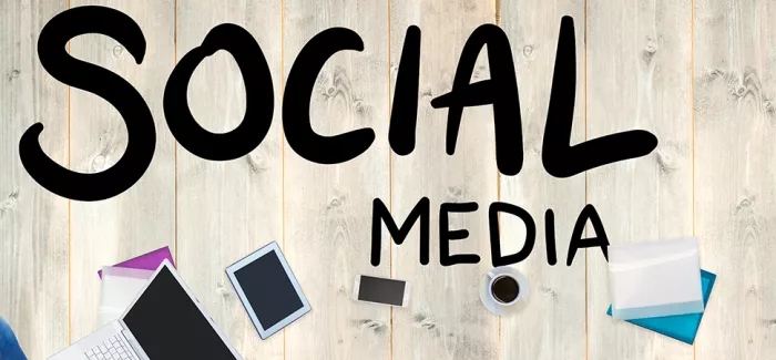 Ein Tisch von oben mit einem Laptop drauf, darüber steht "Social Media"