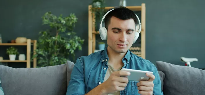 Mann mit Kopfhörern schaut auf sein Smartphone