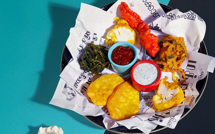 Foto von einem Teller Pakora und Soßen von oben