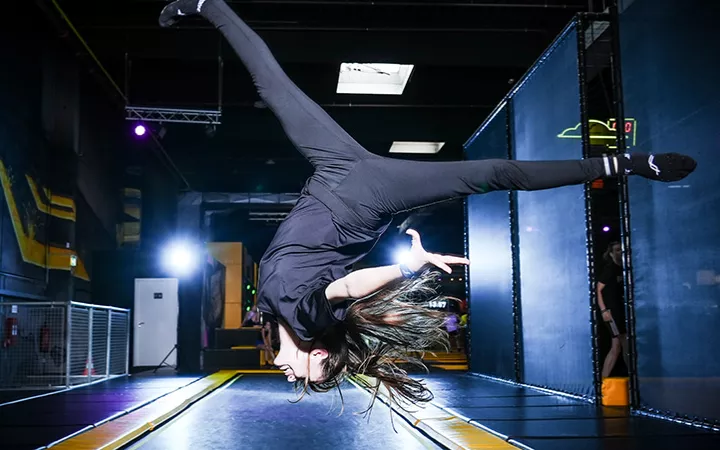 Trampolinspringerin im Superfly München Eine Trampolinspringerin macht überkopf einen Spagat im Sprung