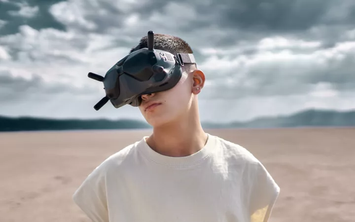 Mann steht in karger Landschaft und hat eine VR Brille auf