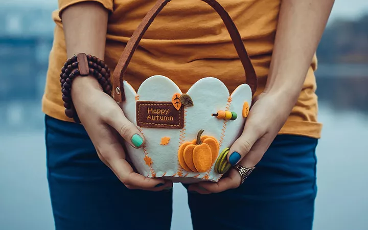 Eine Frau hält einen herbstlichen Korb in beiden Händen.