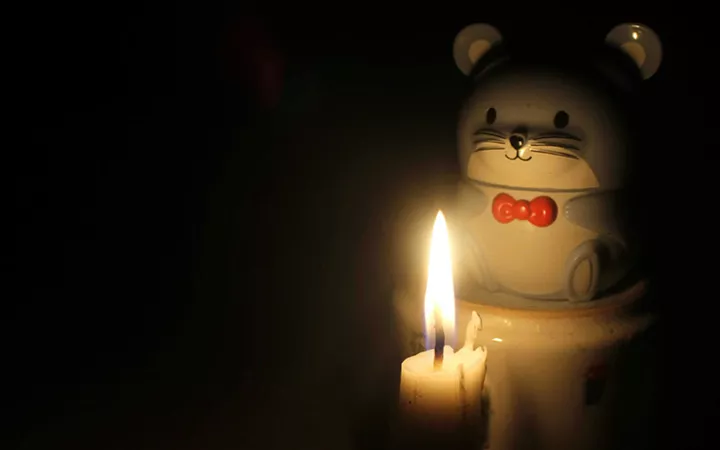 Eine Keramikfigur in Form eines Bärchens wird von Kerzenlicht angeschienen