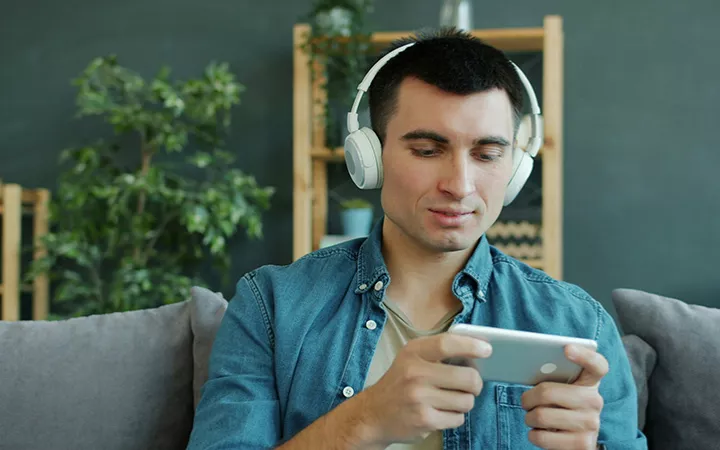 Mann mit Kopfhörern schaut auf sein Smartphone