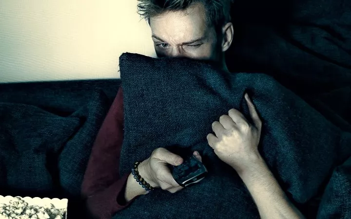 Mann sitzt auf Sofa und gruselt sich Mann Header 970