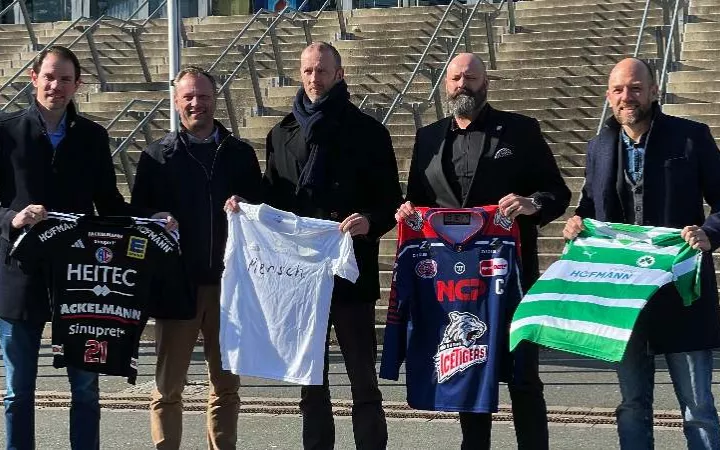 fünf Männer mit Vereinstrikots in der Hand vor der Arena Nürnberger Versicherungen