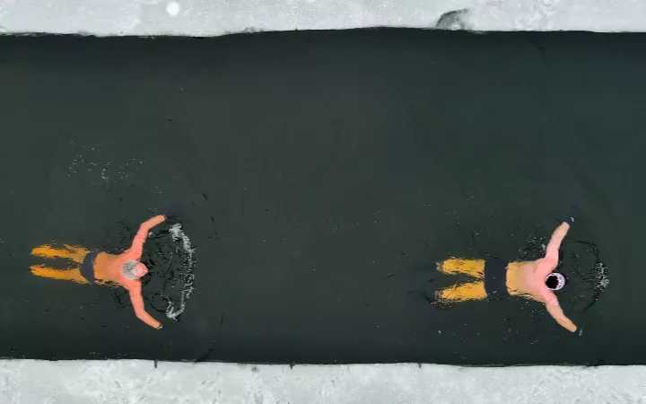 Header Eisbaden 970 Zwei Personen schwimmen im Wasser mit Eis umgeben