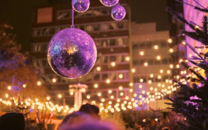 Header Punschwald Discokugeln vor einer weihnachtlich beleuchteten Kulisse mit Tannenbäumen