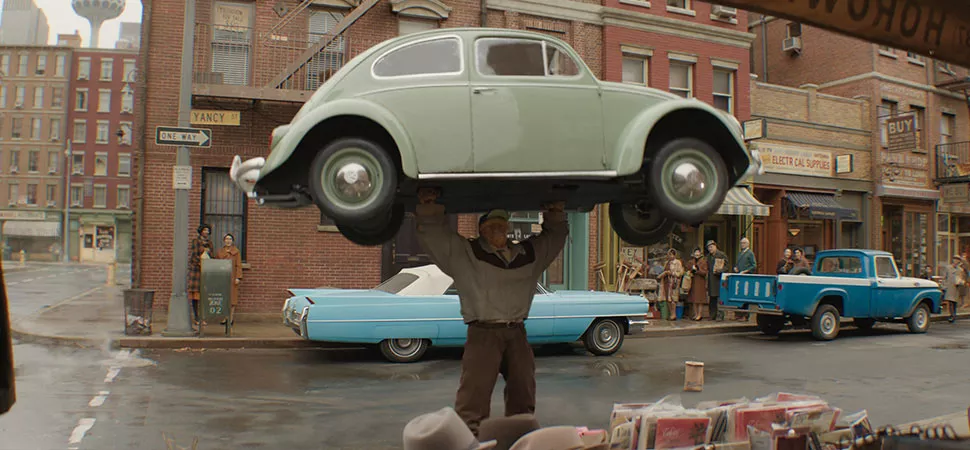Szene aus Fantastic Four: First Steps - Ein Mann stemmt ein Auto in die Höhe