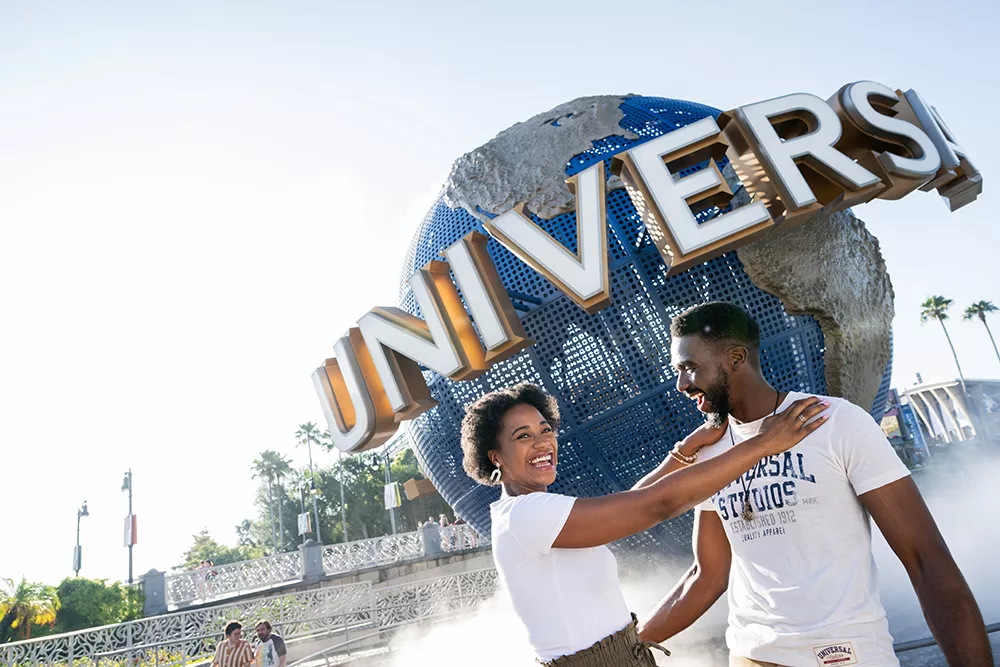 Zwei Personen vor einer großen Weltkugel mit Universal-Schriftzug