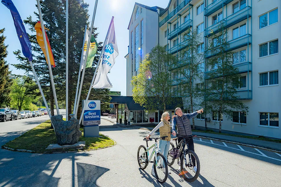 Zwei Personen mit Fahrrädern vor einem Hotel