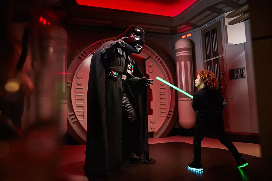 Ein Kind mit einem Laserschwert trifft auf Darth Vader von Star Wars