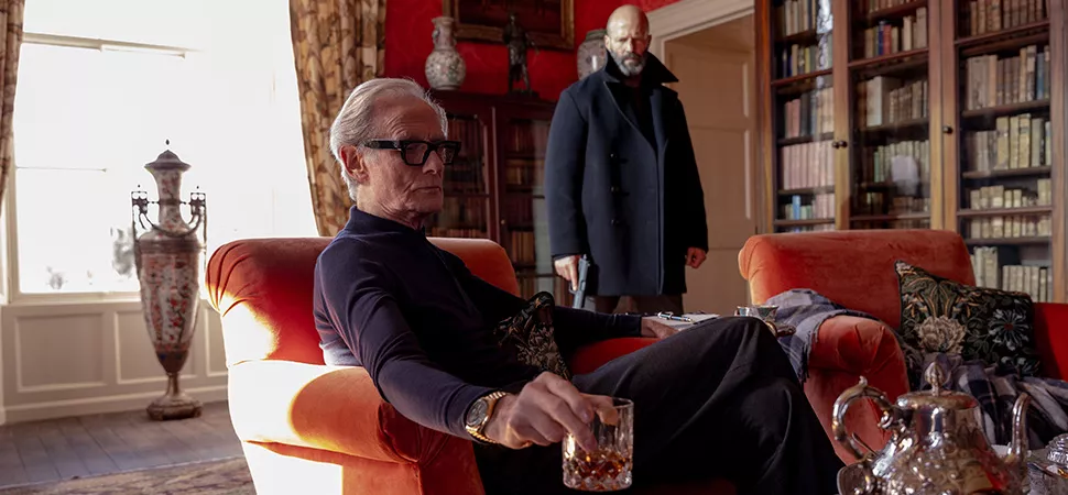 Mann sitzt auf einem Sessel im Hintergrund ein anderer Mann