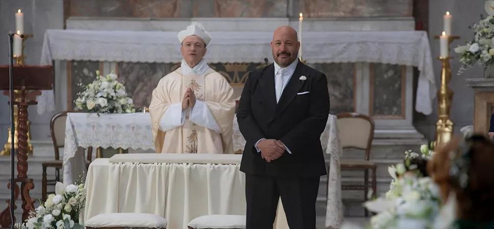Ein Priester und ein Mann im Anzug stehen in einer Kirche